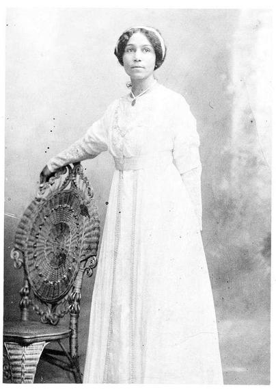Anne B. Spencer in her wedding dress - picryl.com

She is standing with her right hand on the back of a chair.