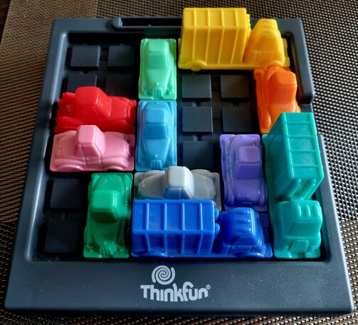 Initial board state. A couple of colorful plastic cars on the board that block the red car.