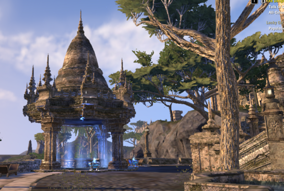 ESO lo-rez in-game screenshot of a paved stone terrace with a masonry pergola in the Khajiit style (a tall bell-shaped roof upheld by four pillars); a gilded pool under the pergola is flanked by two braziers, all of which are emitting pale blue glows upward into the inside of the pergola. Cypress-like trees and gray stone cliffs fill in the background. 