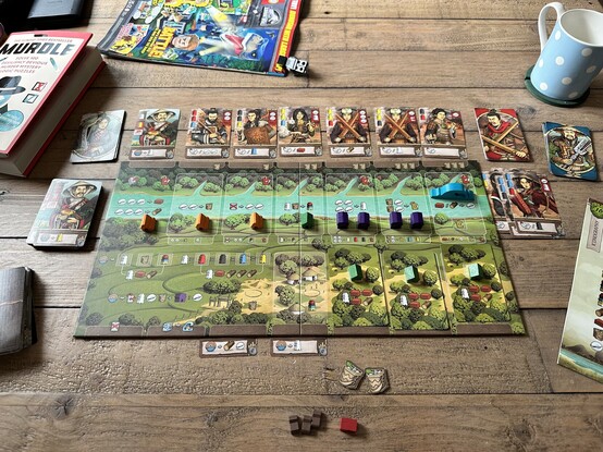 Legacy of Yu board game, showing a canal with fields below it, a ton of barbarian cards on top, and absolutely no villagers left to defend the place except for one dude who’s keeping the dream alive. 