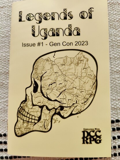 There front cover of "Legends of Uganda" zone. It is printed on yellow paper with an illustration of a skull that has a map of Uganda superimposed over it.