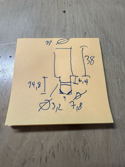 A post-it note it a simple drawing of a part, with all the measurements written around it. 