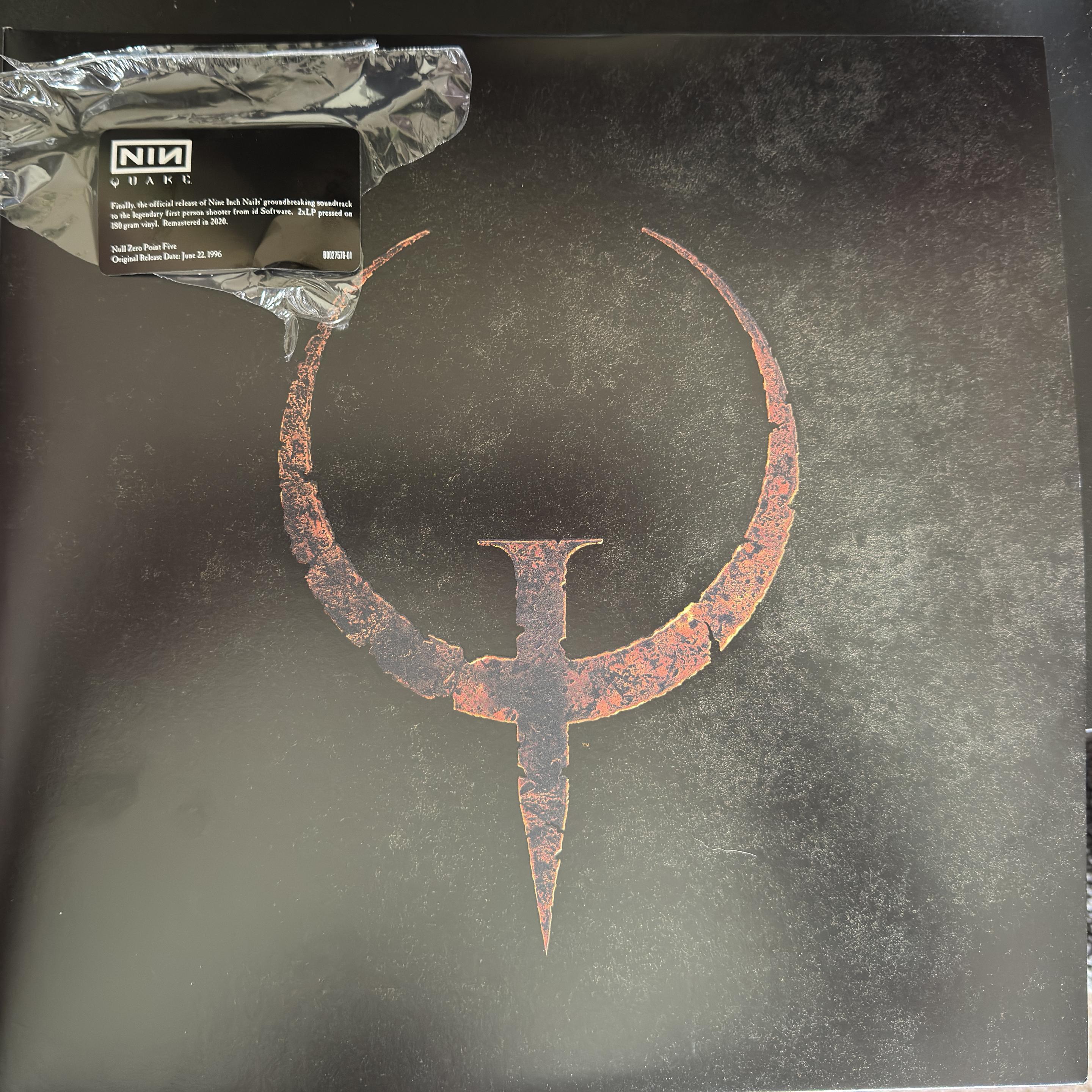 The front cover of the double LP Quake OST by Nine Inch Nails. It shows the iconic logo that looks like partial eclipse with a nail hammered through to make the letter Q