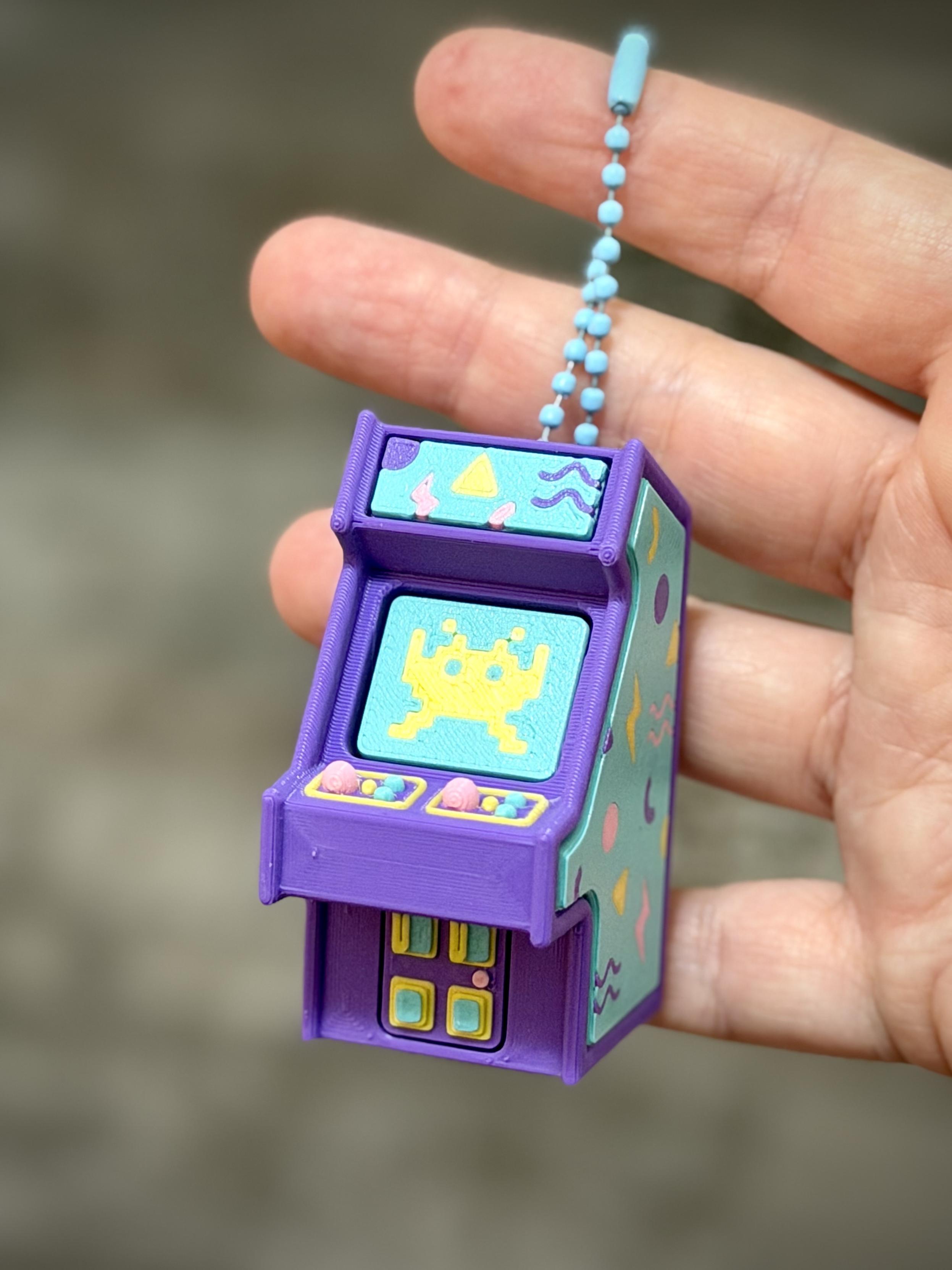 Small mini arcade (purple) with teal sides and retro accents. The screen is a retro alien in yellow on a team background.